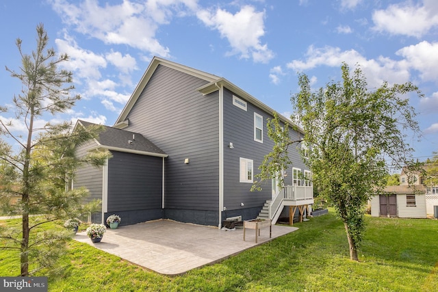 back of property featuring a storage shed, a lawn, stairway, an outdoor structure, and a patio