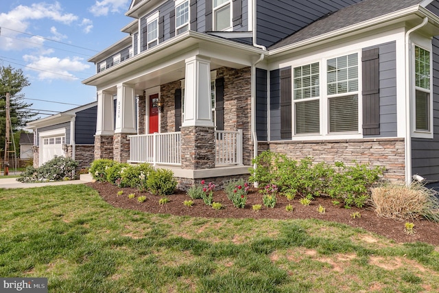 exterior space with a garage, stone siding, and covered porch