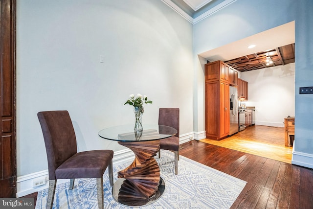 dining area with baseboards, crown molding, and light wood finished floors