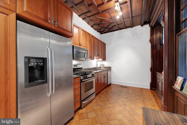 kitchen featuring baseboards, brown cabinets, dark countertops, and appliances with stainless steel finishes