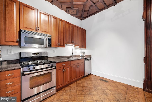 kitchen featuring a sink, brown cabinets, stainless steel appliances, baseboards, and visible vents