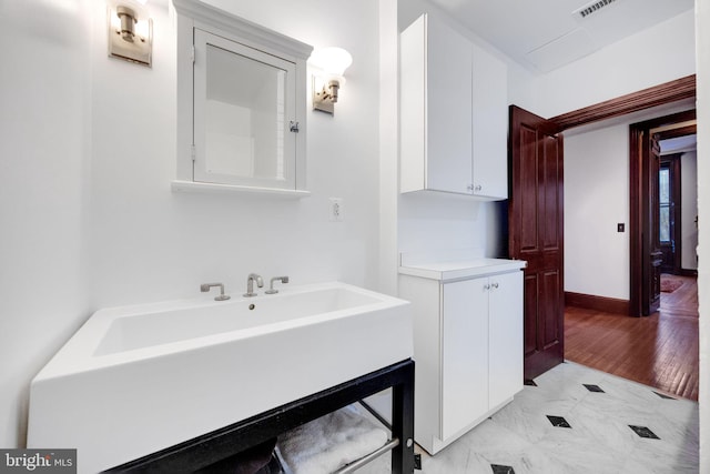 bathroom featuring marble finish floor, a sink, and baseboards