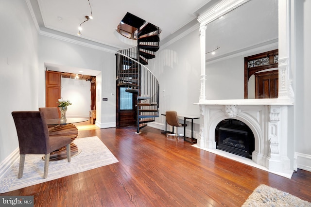 living room featuring a fireplace with flush hearth, stairs, crown molding, and hardwood / wood-style floors
