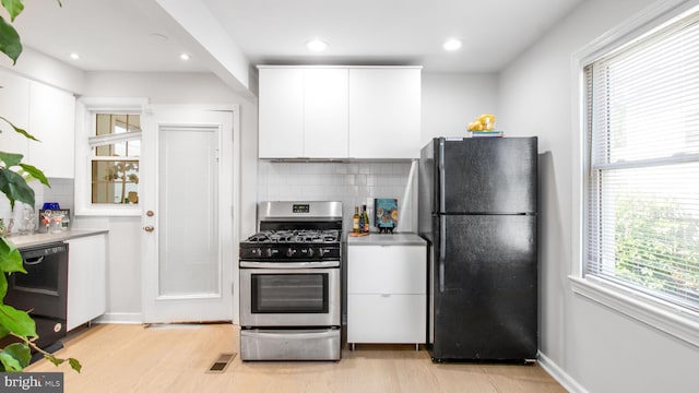 kitchen featuring white cabinets, backsplash, black appliances, and light wood-style floors