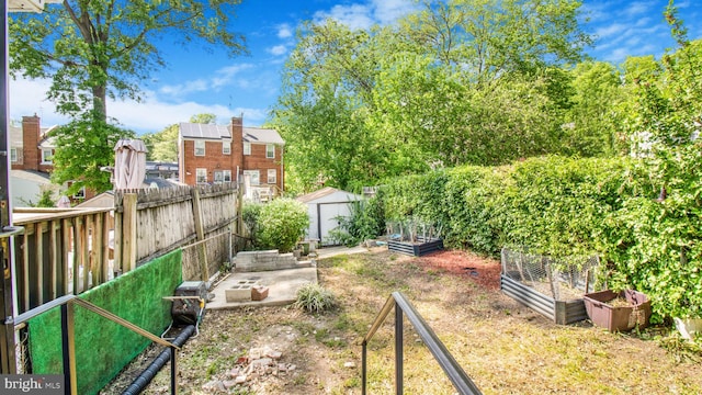 view of yard featuring fence private yard, an outbuilding, a garden, and a shed