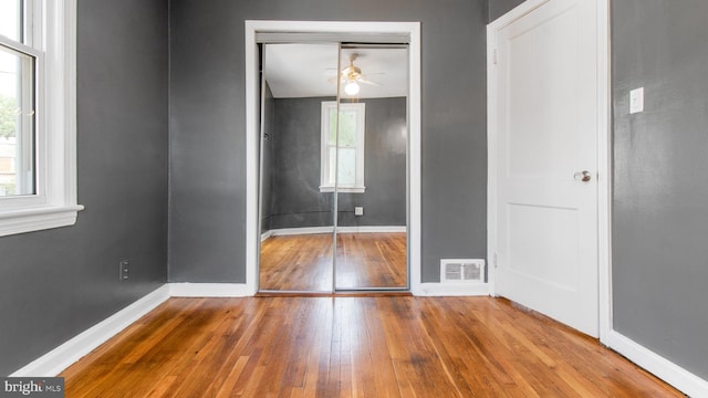 unfurnished bedroom with a closet, baseboards, visible vents, and hardwood / wood-style floors