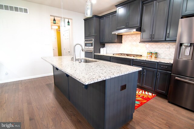 15 N Tompkins Sq, Downingtown, PA 19335 - kitchen with visible vents, a center island with sink, under cabinet range hood, light stone counters, and appliances with stainless steel finishes