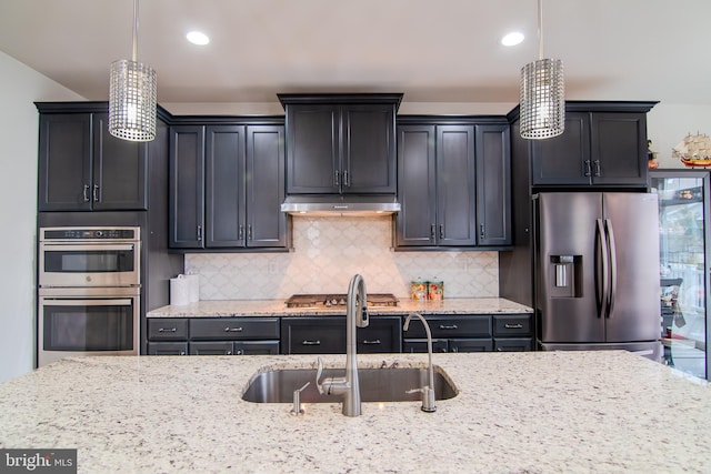 15 N Tompkins Sq, Downingtown, PA 19335 - kitchen featuring light stone counters, a sink, under cabinet range hood, appliances with stainless steel finishes, and tasteful backsplash