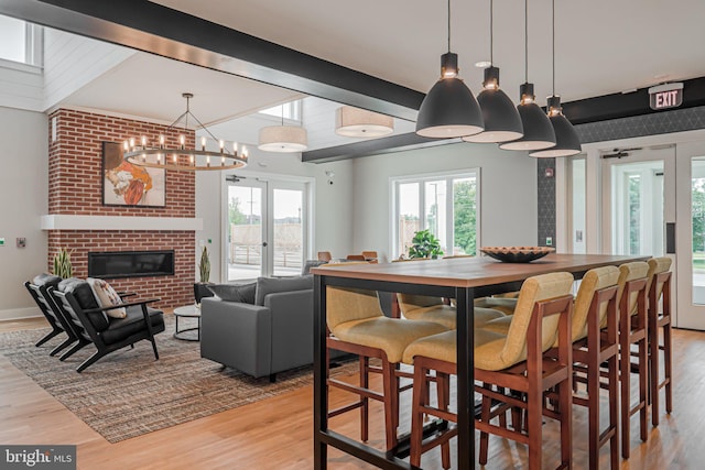 15 N Tompkins Sq, Downingtown, PA 19335 - dining room with light wood-type flooring, beamed ceiling, french doors, an inviting chandelier, and a brick fireplace