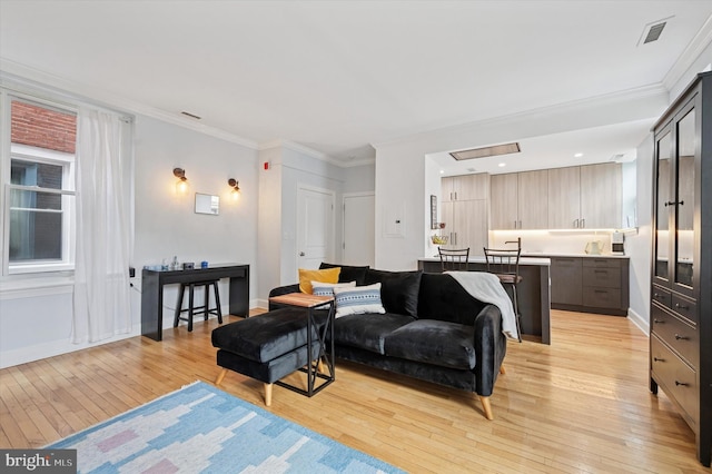 living area with light wood-style flooring, crown molding, and baseboards