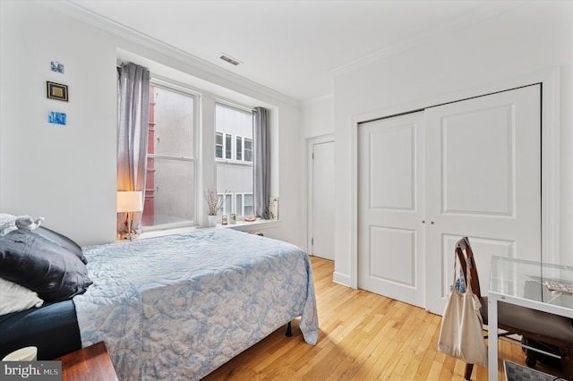 bedroom featuring ornamental molding, wood-type flooring, and a closet