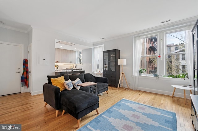 living room featuring light wood-style flooring, ornamental molding, and baseboards
