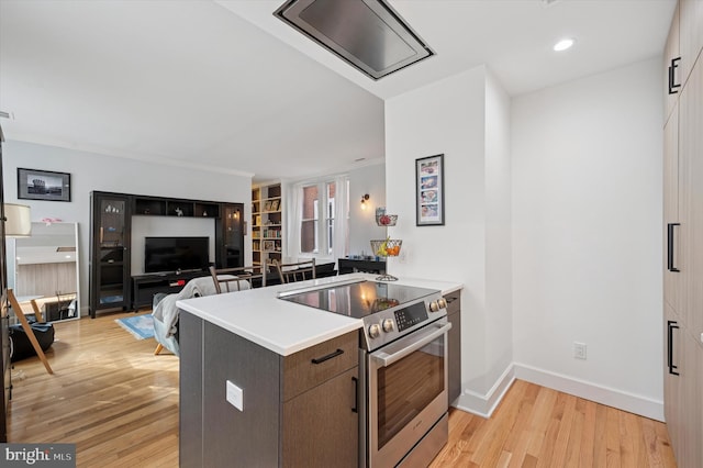 kitchen featuring electric range, a peninsula, light wood finished floors, light countertops, and recessed lighting