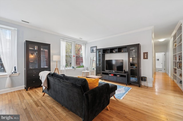 living area with light wood-style floors, crown molding, and baseboards