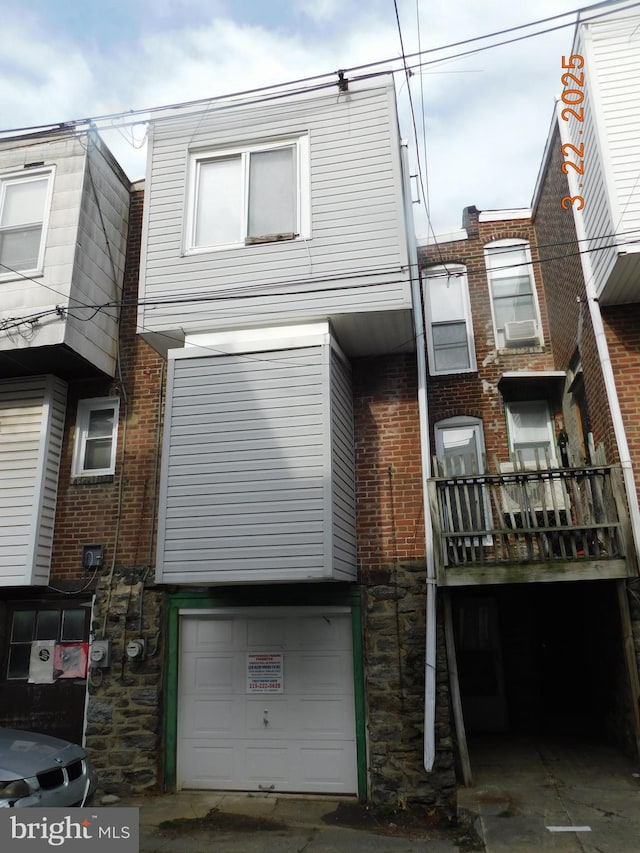 rear view of property featuring stone siding and an attached garage