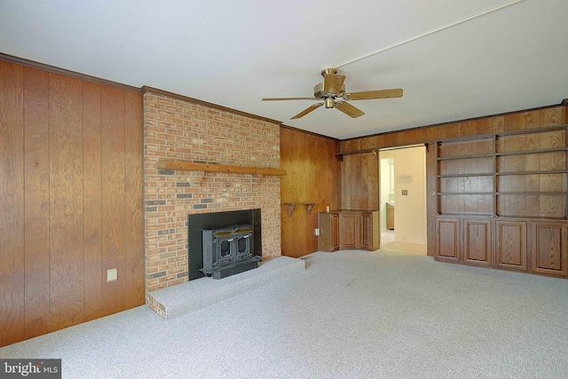 3360 Ben Oak Dr, Huntingtown, MD 20639 - carpeted living room featuring crown molding, wooden walls, a wood stove, and a ceiling fan