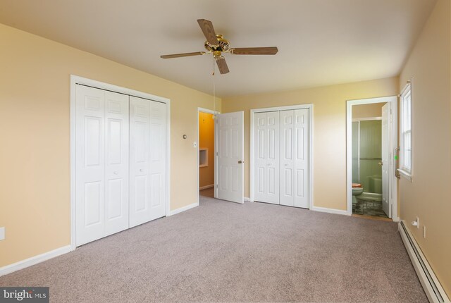 unfurnished bedroom featuring a baseboard heating unit, baseboards, carpet flooring, and two closets