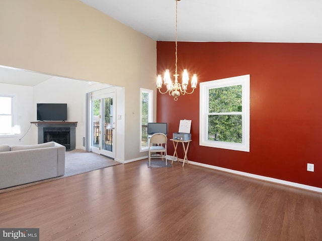interior space featuring a fireplace with flush hearth, a wealth of natural light, wood finished floors, and a chandelier