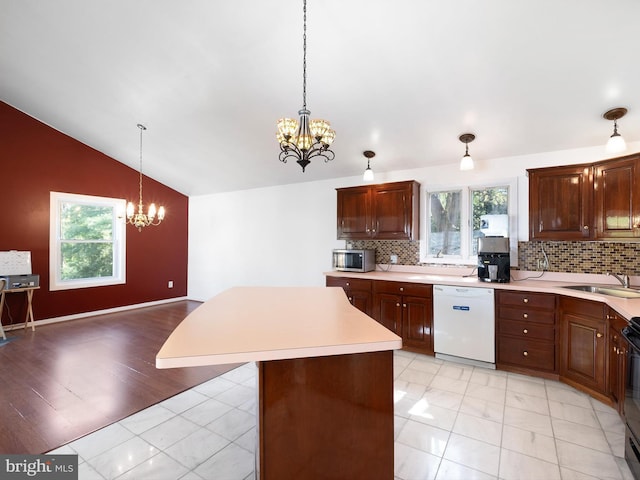 kitchen featuring lofted ceiling, light countertops, a chandelier, a sink, and dishwasher