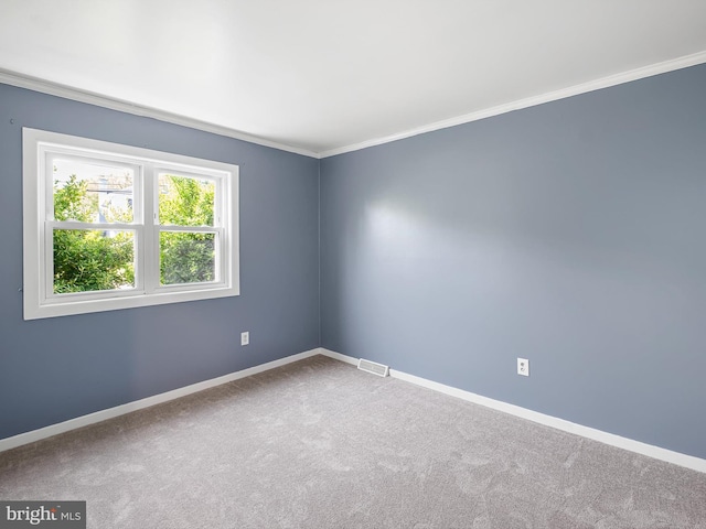 carpeted spare room featuring crown molding, baseboards, and visible vents
