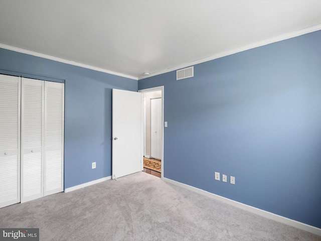 unfurnished bedroom with visible vents, crown molding, a closet, baseboards, and carpet