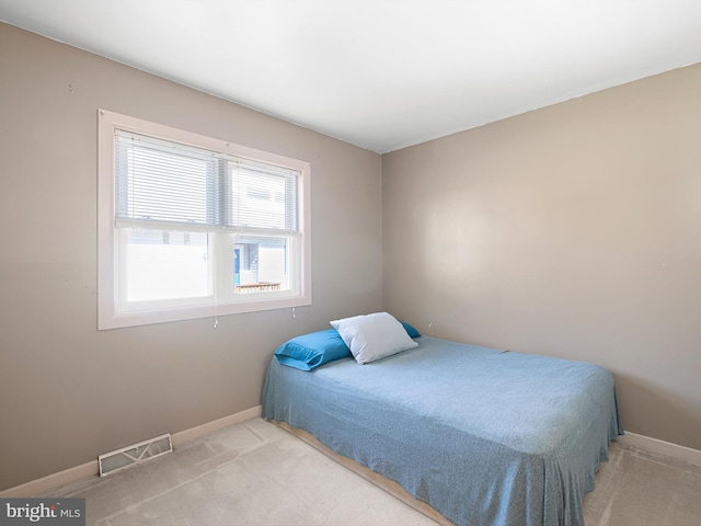 bedroom featuring baseboards, light carpet, and visible vents