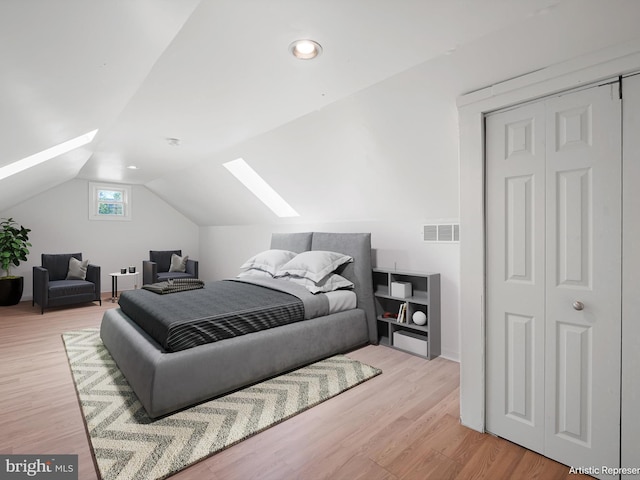 bedroom with visible vents, light wood-style flooring, and vaulted ceiling with skylight