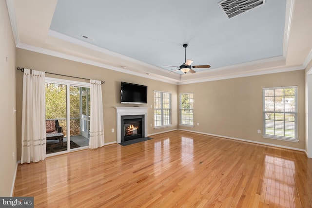 unfurnished living room featuring a raised ceiling, visible vents, and a wealth of natural light