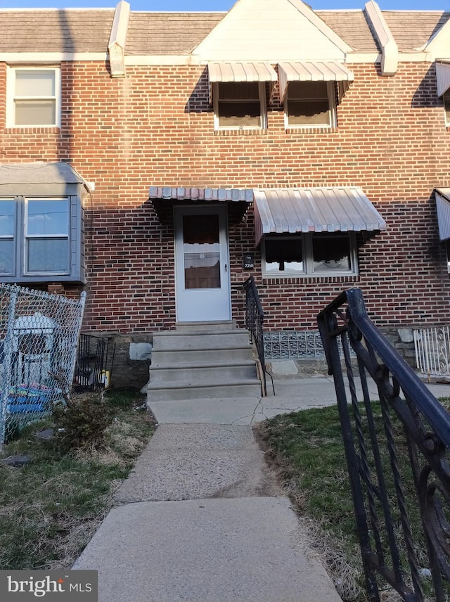 townhome / multi-family property featuring brick siding, fence, and entry steps