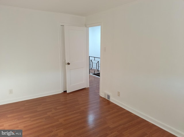 unfurnished room featuring baseboards, visible vents, and wood finished floors