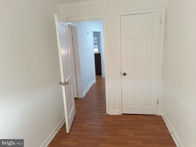 corridor with baseboards and dark wood finished floors