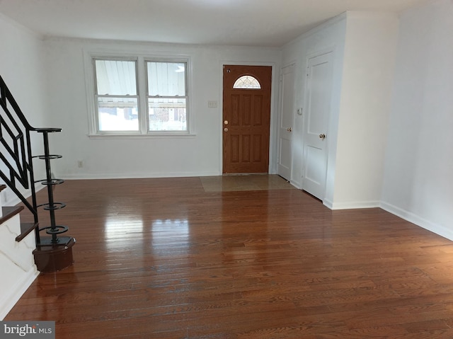 foyer entrance with stairs, wood finished floors, and baseboards