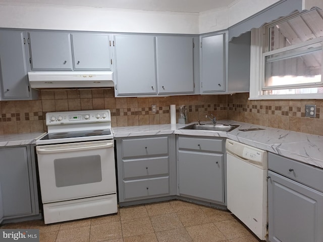 kitchen featuring gray cabinets, a sink, tasteful backsplash, under cabinet range hood, and white appliances