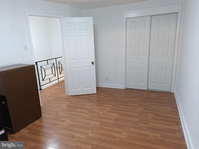 unfurnished bedroom featuring a closet, baseboards, and wood finished floors