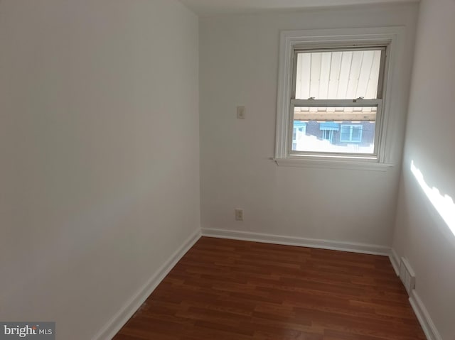 empty room with baseboards, visible vents, and wood finished floors