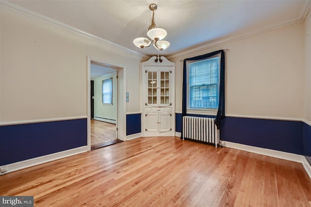 empty room with radiator heating unit, a chandelier, light wood finished floors, a baseboard radiator, and crown molding