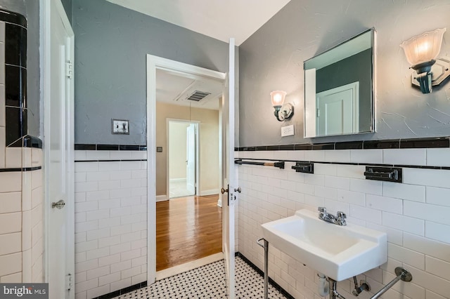 bathroom featuring tile walls, a sink, and a wainscoted wall