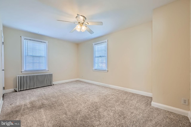 empty room featuring radiator heating unit, carpet, a ceiling fan, and baseboards