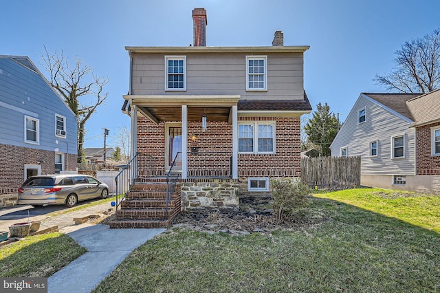 view of front of property featuring a chimney, brick siding, and a porch