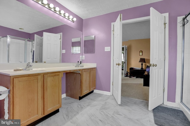 ensuite bathroom with a textured ceiling, marble finish floor, a sink, a stall shower, and double vanity