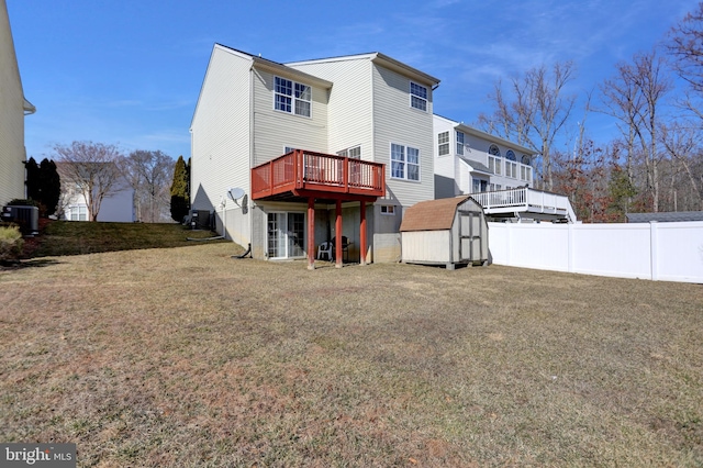 back of property with fence, a deck, an outdoor structure, a storage unit, and a lawn