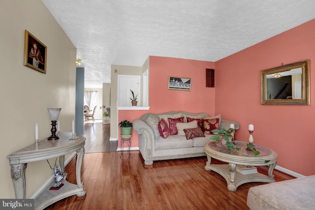living area featuring a textured ceiling, baseboards, and wood finished floors
