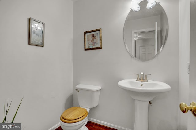half bath featuring baseboards and toilet