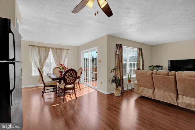 dining space with hardwood / wood-style floors, a ceiling fan, baseboards, and a textured ceiling