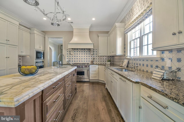 kitchen featuring a sink, light stone counters, custom exhaust hood, and appliances with stainless steel finishes