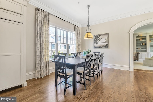 dining space with dark wood-style flooring, arched walkways, crown molding, and baseboards