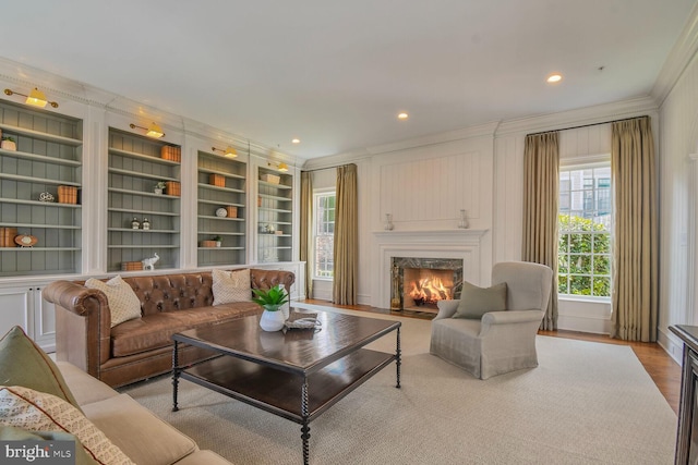 living room with crown molding, recessed lighting, built in shelves, a fireplace, and wood finished floors