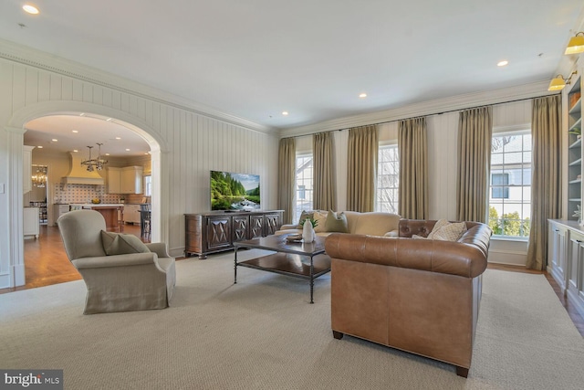 living area with an inviting chandelier, arched walkways, crown molding, and recessed lighting