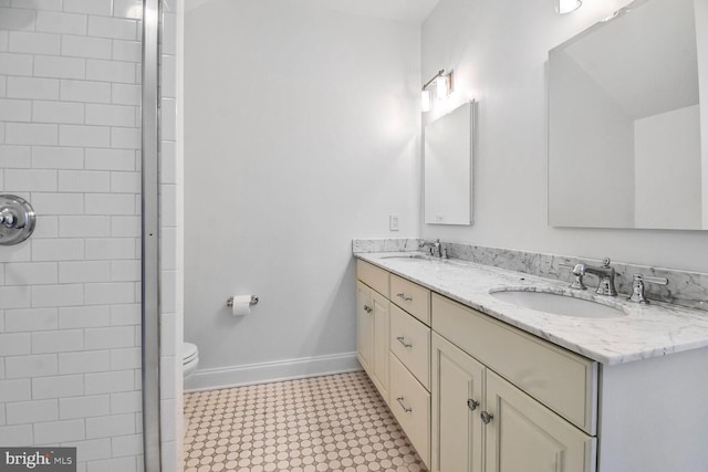 full bath with baseboards, double vanity, a sink, and toilet