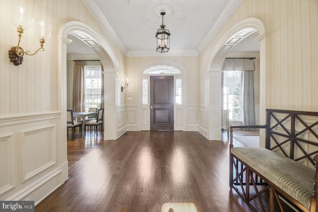 entrance foyer featuring plenty of natural light, arched walkways, and dark wood finished floors